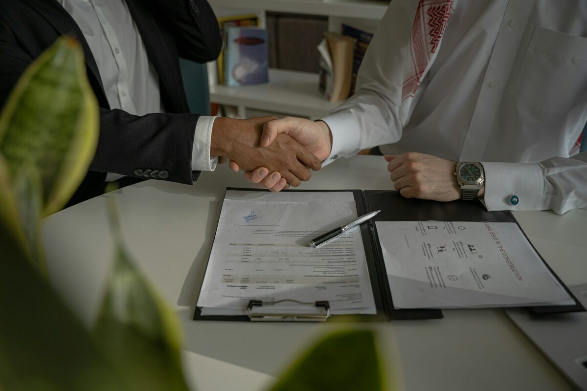 Aperto de mãos sobre documento de contrato em mesa de reunião