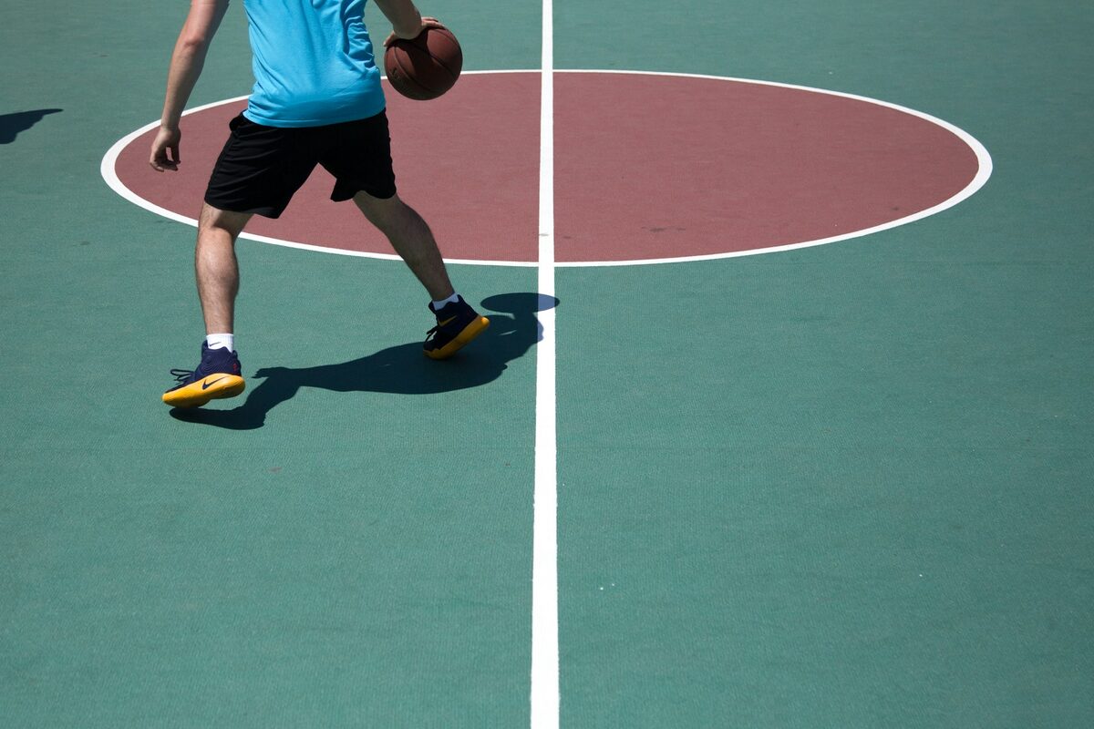 Jogador conduz a bola na quadra ao ar livre