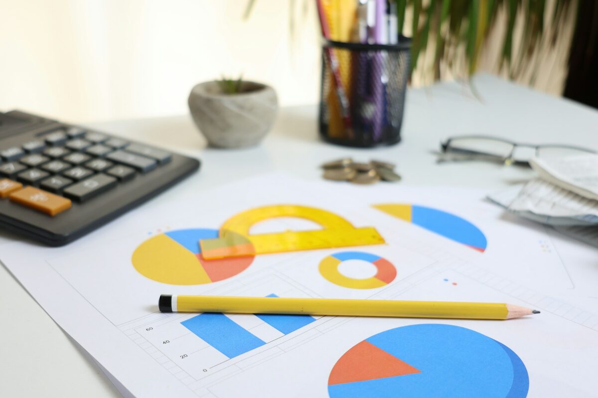 Mesa de trabalho com planilha orçamentária, gráficos e calculadora — contexto típico da elaboração do orçamento de um projeto da Lei de Incentivo ao Esporte